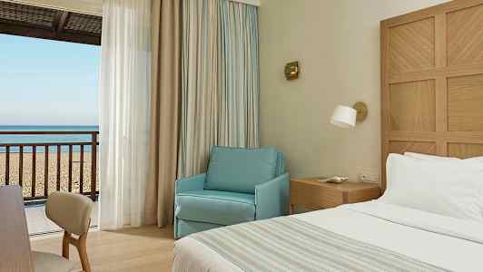 Hotellrum med utsikt mot sandstrand och hav. (AI-genererad text)