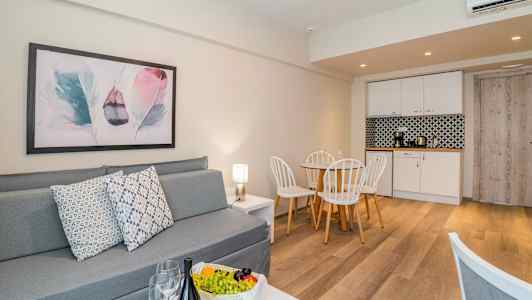 Ett modernt vardagsrum med grå soffa, matbord och ett kök i bakgrunden. (AI-genererad text)