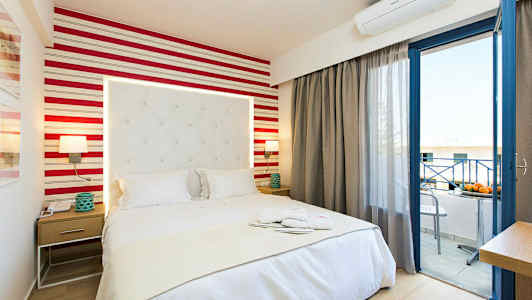 Ett hotellrum med en säng, nattduksbord och öppen balkongdörr. (AI-genererad text)