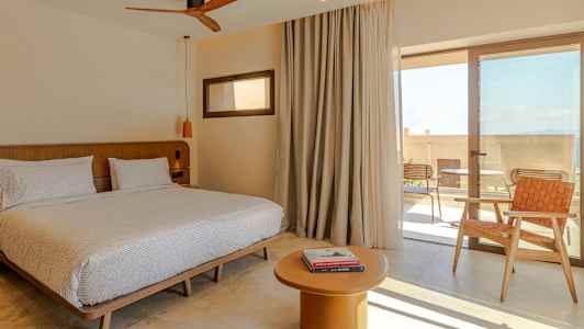 Rum med dubbelsäng, bord och stol, samt glasdörr till terrass. (AI-genererad text)