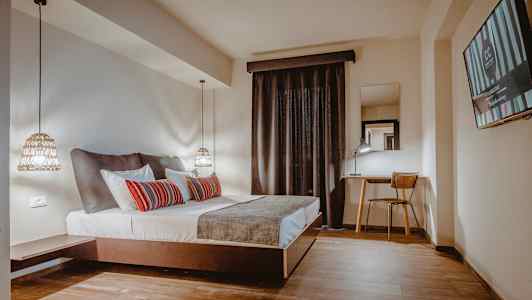 Ett hotellrum med en dubbelsäng, skrivbord och stol samt en tv på väggen. (AI-genererad text)