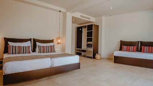 Ett hotellrum med en stor säng, dekorativa kuddar och en öppen garderob. (AI-genererad text)