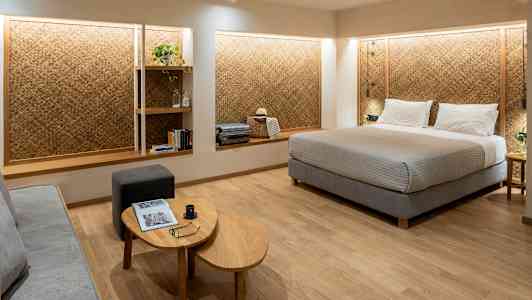 Ett hotellrum med en stor säng, en sittplats och hyllor på väggen. (AI-genererad text)