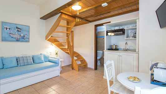 Ett rum med trämöbler, en spiraltrappa, en soffa och ett bord. (AI-genererad text)