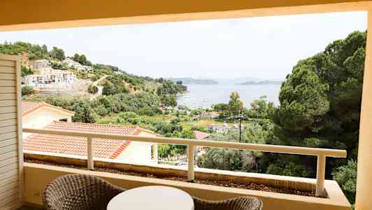 Utsikt från en balkong över grönska, byggnader och en vik. (AI-genererad text)