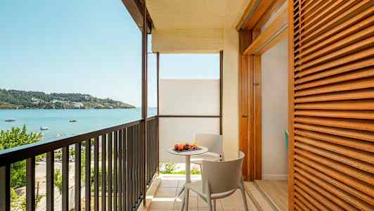Balkong med utsikt över havet och ett bord med frukt. (AI-genererad text)