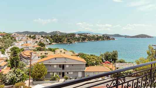 Utsikt över en kuststad med röda tak och havet i bakgrunden. (AI-genererad text)