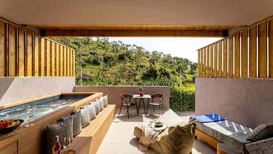 En uteplats med badkar, sittmöbler och en utsikt över grön natur. (AI-genererad text)