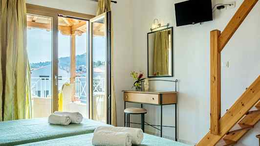 Ett hotellrum med två enkelsängar, en spegel med ett skrivbord, en balkongdörr och en väggmonterad TV. (AI-genererad text)