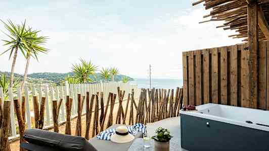 Privat veranda med havsutsikt, solsäng och badkar. (AI-genererad text)