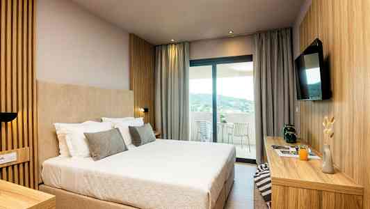 Hotellrum med en stor säng, modern inredning och utsikt mot en terrass. (AI-genererad text)