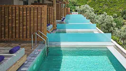 Privata pooler med solstolar och utsikt över grönskande natur. (AI-genererad text)