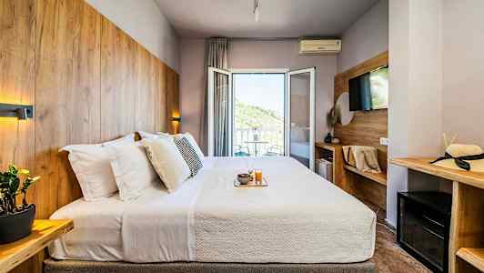 Hotellrum med en dubbelsäng, utsmyckat med träpaneler och en balkong med utsikt. (AI-genererad text)