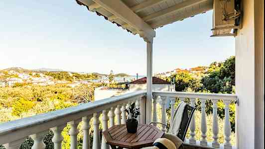 En balkong med en utsikt över ett landskap med hus och träd. (AI-genererad text)