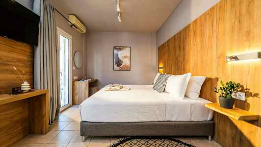 Ett modernt hotellrum med en stor säng, träpaneler på väggen och en växt på en hylla. (AI-genererad text)