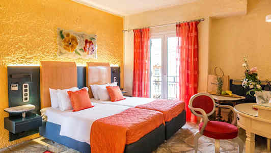 Ett hotellrum med två sängar, orange inredning och röda gardiner, samt ett mindre bord med stolar och dekorationer. (AI-genererad text)