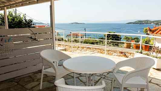 Utomhusområde med vita plastmöbler och utsikt över havet. (AI-genererad text)