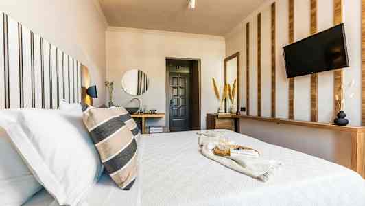 Ett modernt hotellrum med en bäddad säng, dekorativa träpaneler och en TV på väggen. (AI-genererad text)