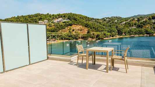 Utsikt från en terrass över havet med en stol och ett bord. (AI-genererad text)