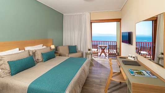 Hotellrum med dubbelsäng och balkong med havsutsikt. (AI-genererad text)