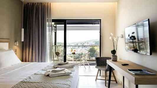 Hotelrum med säng, TV, skrivbord och balkong med utsikt. (AI-genererad text)