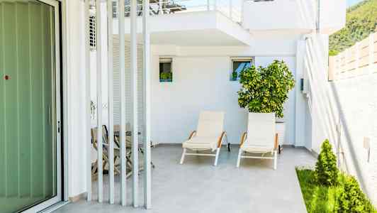 Bild av en uteplats med solstolar och växtlighet. (AI-genererad text)