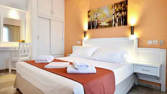 Hotellrum med en dubbelsäng, nattduksbord, garderob och en målning på väggen. (AI-genererad text)