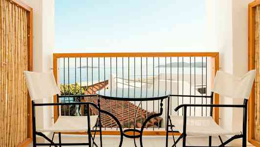 En balkong med två vita stolar och ett bord med havsutsikt. (AI-genererad text)