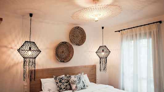 Ett sovrum med dekorativa taklampor, en säng med kuddar och väggdekorationer. (AI-genererad text)