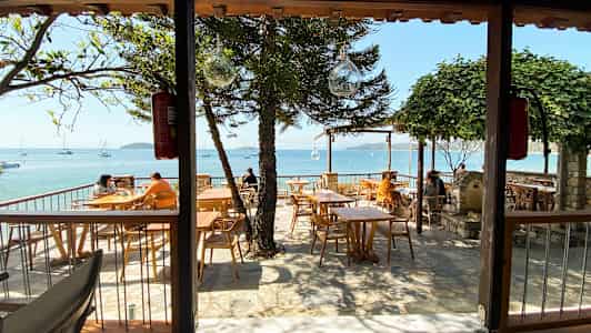 Uterestaurang med havsutsikt och träbord. (AI-genererad text)