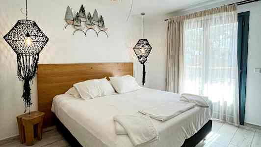 Sovrum med dubbelsäng, vita sängkläder och dekorativa lampor i en modern design. (AI-genererad text)