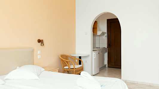 Ett hotellrum med en säng, stol och ett öppet kök. (AI-genererad text)