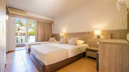 Ett hotellrum med två enkelsängar, nattygsbord och en balkongdörr med utsikt. (AI-genererad text)