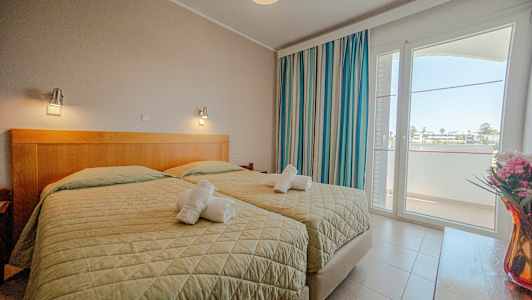 Ett hotellrum med två enkelsängar, fönster och dekorationer. (AI-genererad text)