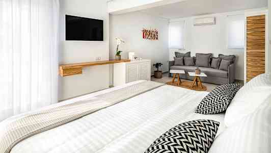 Ett ljus, modernt hotellrum med säng, soffa och TV. (AI-genererad text)