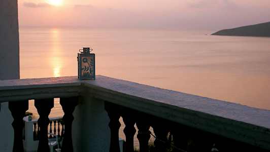 Utsikt från en balkong med en dekorativ ljuslykta, solnedgång över havet. (AI-genererad text)