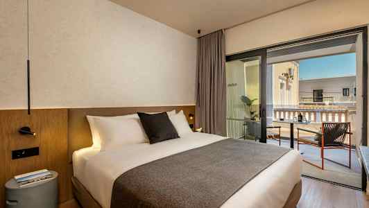 En hotellrum med en dubbelsäng och en balkong med sittplatser. (AI-genererad text)