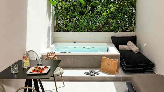 En utomhusmiljö med ett spabad, solstolar och ett bord med dryck och snacks. (AI-genererad text)