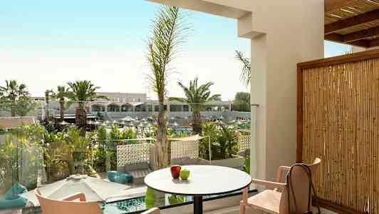 Utsikt från en terrass med bord, stolar och dekorativ växtlighet. (AI-genererad text)