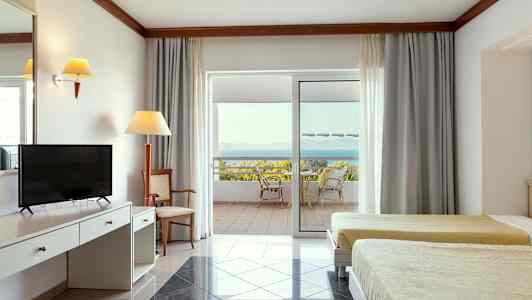 Interiör av ett hotellrum med två sängar, skrivbord och en uteplats med utsikt över havet. (AI-genererad text)