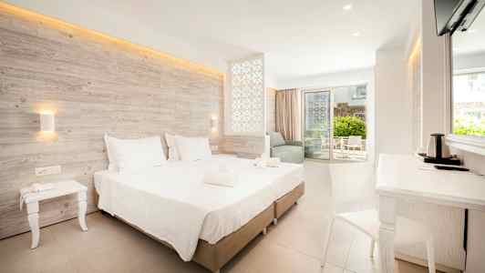 Modernt hotellrum med dubbelsäng, sittgrupp och balkong. (AI-genererad text)