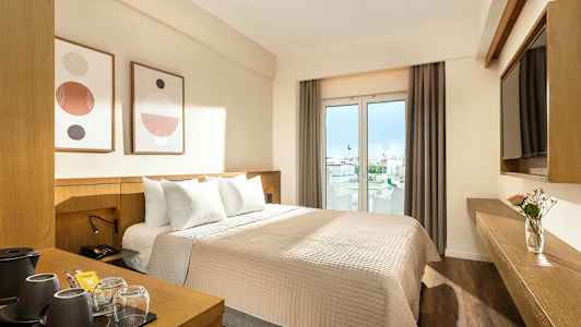 Ett hotellrum med en dubbelsäng, modern inredning och fönster som visar utsikt mot staden. (AI-genererad text)