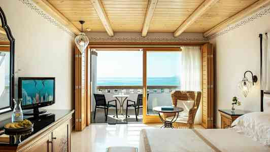 En hotellrum med utsikt över havet, inklusive en balkong med sittplatser. (AI-genererad text)