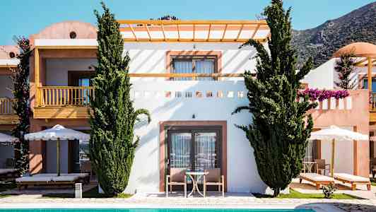 En bild av en byggnad med terrass och balkong, omgärdad av gröna träd och med en pool i förgrunden. (AI-genererad text)