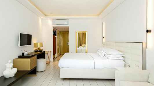 Ett modernt hotellrum med en dubbelsäng, väggmonterad TV, skrivbord och stolar. (AI-genererad text)