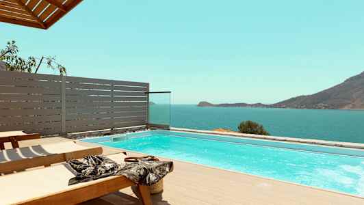 Solstolar vid en pool med utsikt över havet och berg. (AI-genererad text)