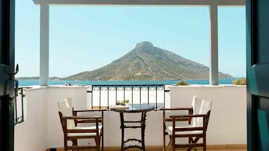 Veranda med två stolar och ett bord, utsikt mot havet och berg. (AI-genererad text)