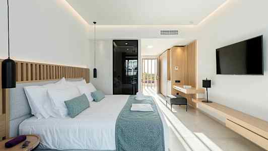 Modernt hotellrum med dubbelsäng, bortre fönster och inredning i ljusa toner. (AI-genererad text)