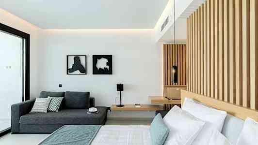 Ett modernt hotellrum med en säng, en soffa och en träpanelvägg. (AI-genererad text)