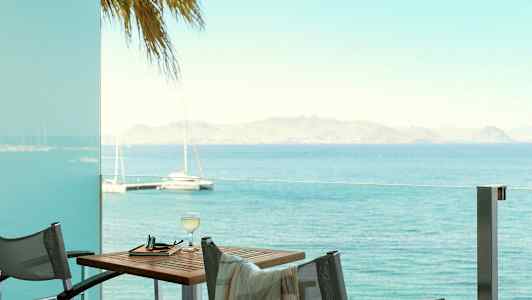 Utsikt över havet från en altan med bord och stolar. (AI-genererad text)